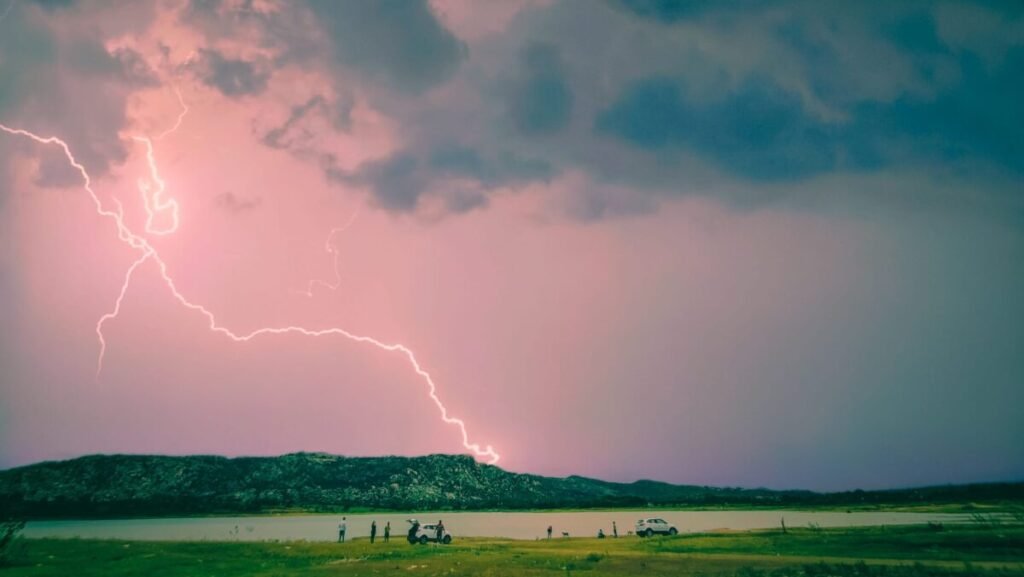 Bolt of lightning streaking across a rosy sky filled with dark, billowing storm clouds